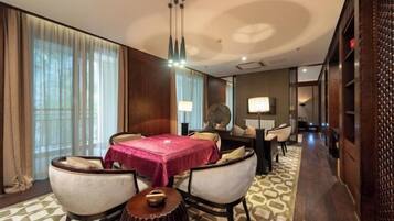 A hotel room with a dining area, a round table with a red tablecloth, and a patterned carpet.