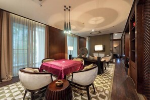 A hotel room with a dining area, a round table with a red tablecloth, and a patterned carpet. - Nanchang Qinyuan Villa (Nanchang)