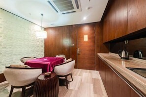 A modern kitchen with wooden cabinets, a marble countertop, and a dining area with a table and chairs. - Nanchang Qinyuan Villa (Nanchang)