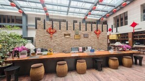 A reception area with a wooden counter, several stools, a glass ceiling, and red lanterns. - Nanchang Qinyuan Villa (Nanchang)
