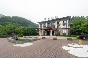 A hotel with a traditional architectural style, featuring a large entrance, a courtyard with a fountain, and a well-maintained garden.