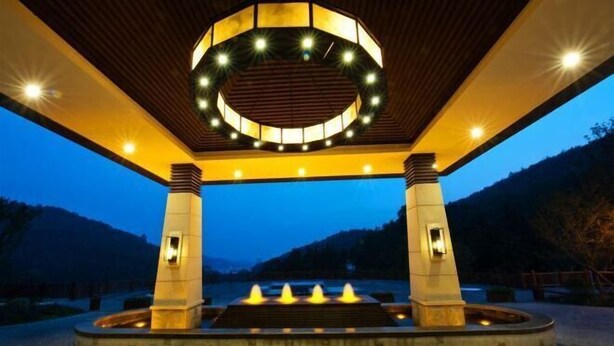 A well-lit outdoor area with a circular water feature and steps leading up to it, surrounded by a wooden structure with a circular light fixture above. - Nanchang Qinyuan Villa (Nanchang)