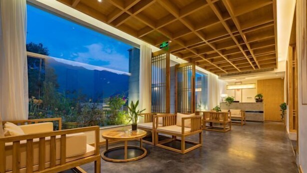 A spacious lobby with wooden furniture, a large aquarium window, and a reception desk. - Zhangjiajie Wulingyuan Bamboo Holiday Homestay (Zhangjiajie)