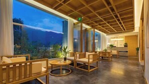 A spacious lobby with wooden furniture, large windows, and a view of a mountainous landscape. - Zhangjiajie Wulingyuan Bamboo Holiday Homestay (Zhangjiajie)