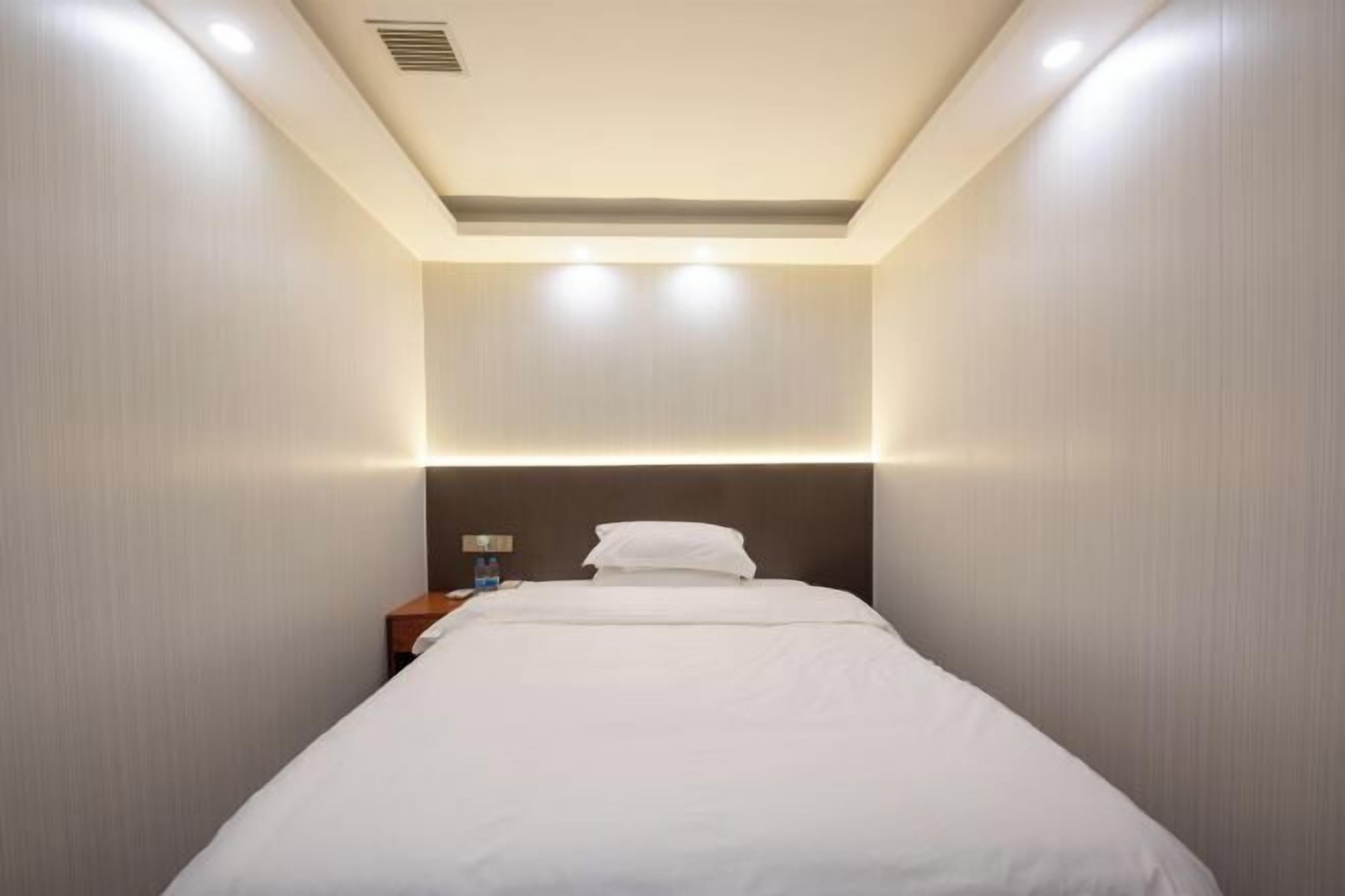 Een hotelkamer met een bed, nachtkastje en een wandlamp.