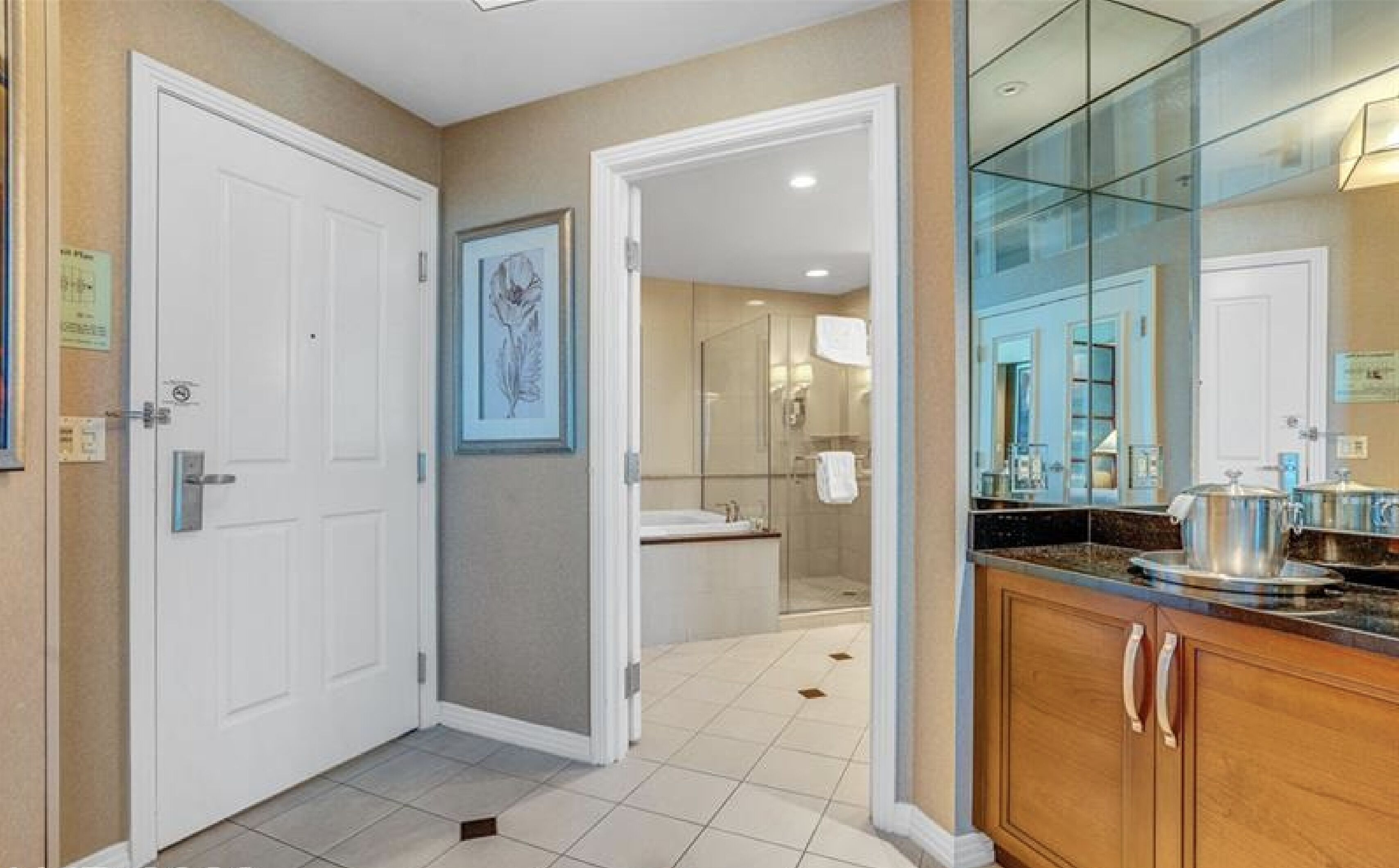 A hotel bathroom with a glass shower enclosure, a sink, and a mirror.