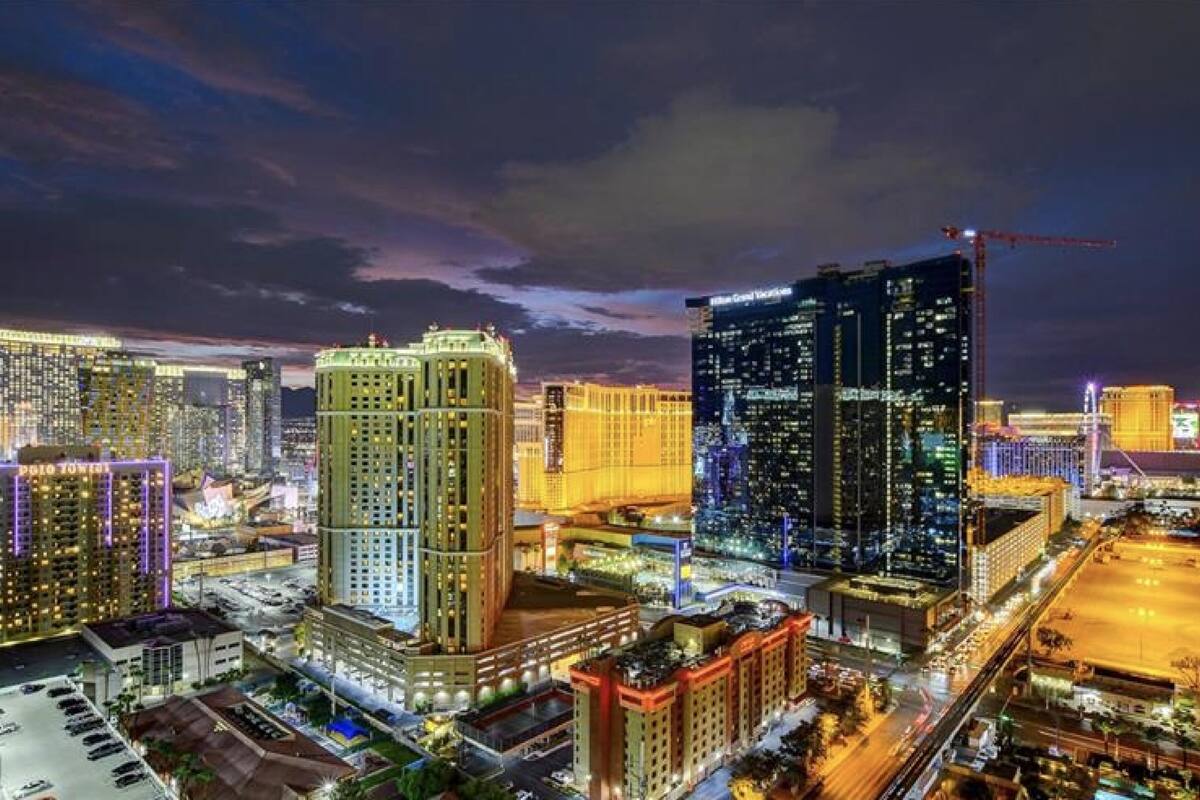 A cityscape at night with illuminated buildings, including a hotel with a prominent sign.