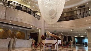 A grand lobby with a large chandelier, a grand piano, and a circular marble floor. - Qinheyuan Linxuan Holiday Hotel (Haining)