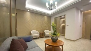 A modern lobby with a grey sofa, two armchairs, a wooden coffee table, and a chandelier. - Qinheyuan Linxuan Holiday Hotel (Haining)