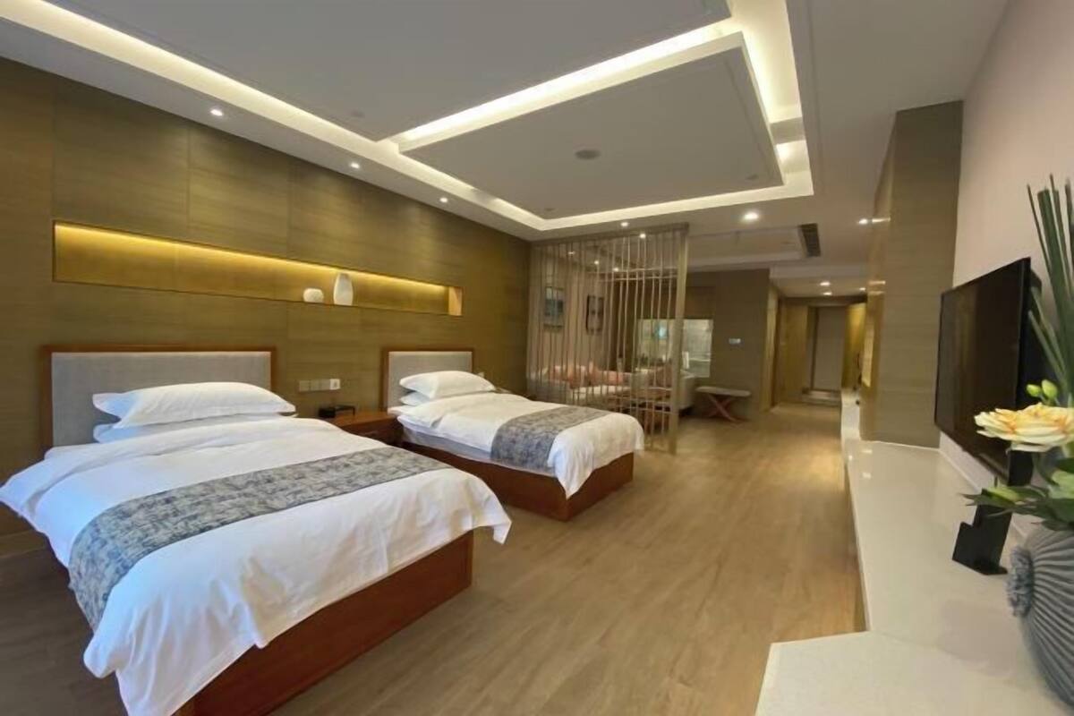 A modern hotel room with two beds, a wooden floor, and a large mirror.