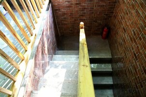 Una escalera con barandilla amarilla, pasamanos de madera y pared de ladrillo.