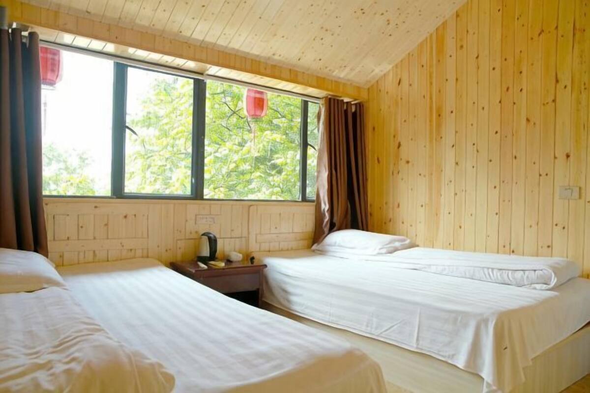 Une chambre avec deux lits, une fenêtre avec des rideaux et un mur en bois.