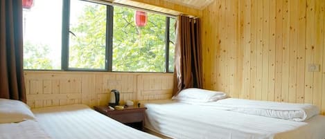 Una habitación con dos camas, una ventana con cortinas y una pared de madera.