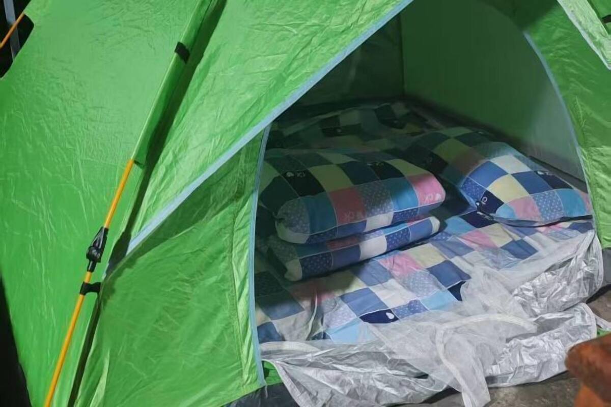 Une tente avec une toile extérieure verte et un matelas matelassé à l’intérieur.