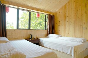 Une chambre avec deux lits, une fenêtre avec des rideaux et un mur en bois.