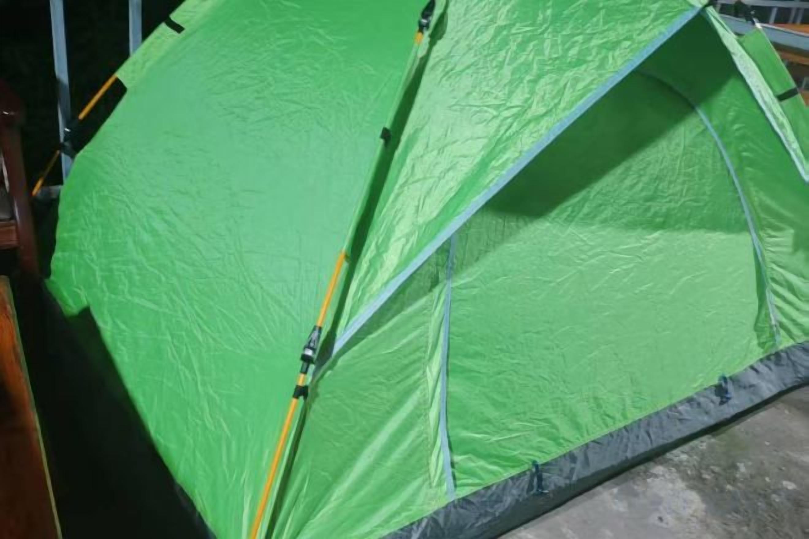Une structure verte en forme de tente, dotée d’un toit incurvé, qui pourrait être un abri temporaire ou faire partie d’une installation plus vaste.