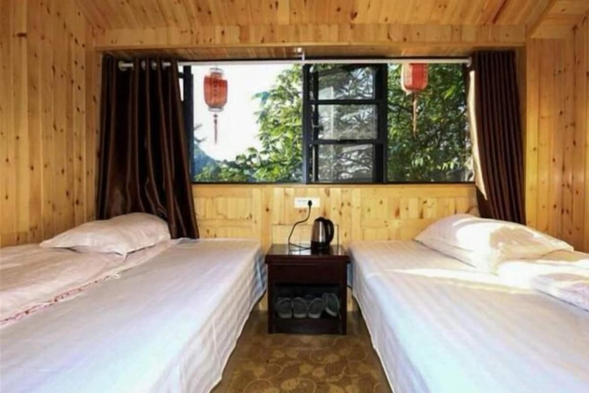 Une chambre avec deux lits, une fenêtre avec des rideaux et une petite table avec une bouilloire.