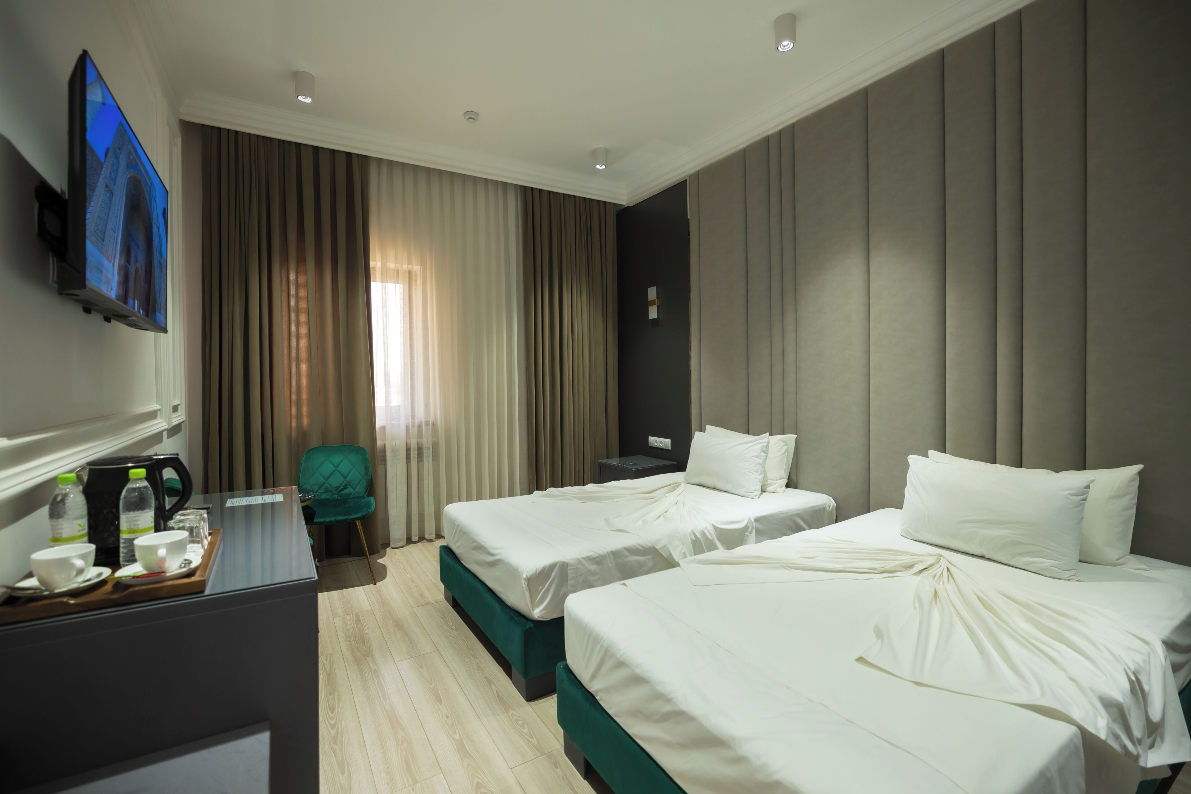 Une chambre d’hôtel avec deux lits, une télévision, un bureau avec une machine à café et une chaise.