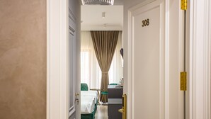 Habitación de hotel con cama, escritorio y una silla. La habitación tiene una puerta con el número 308.
