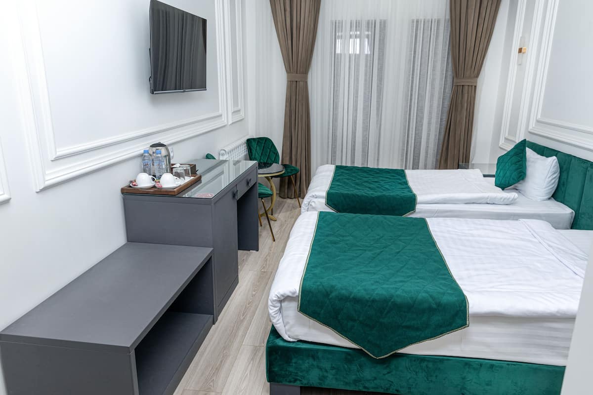 A hotel room with two beds, a desk, and a chair.