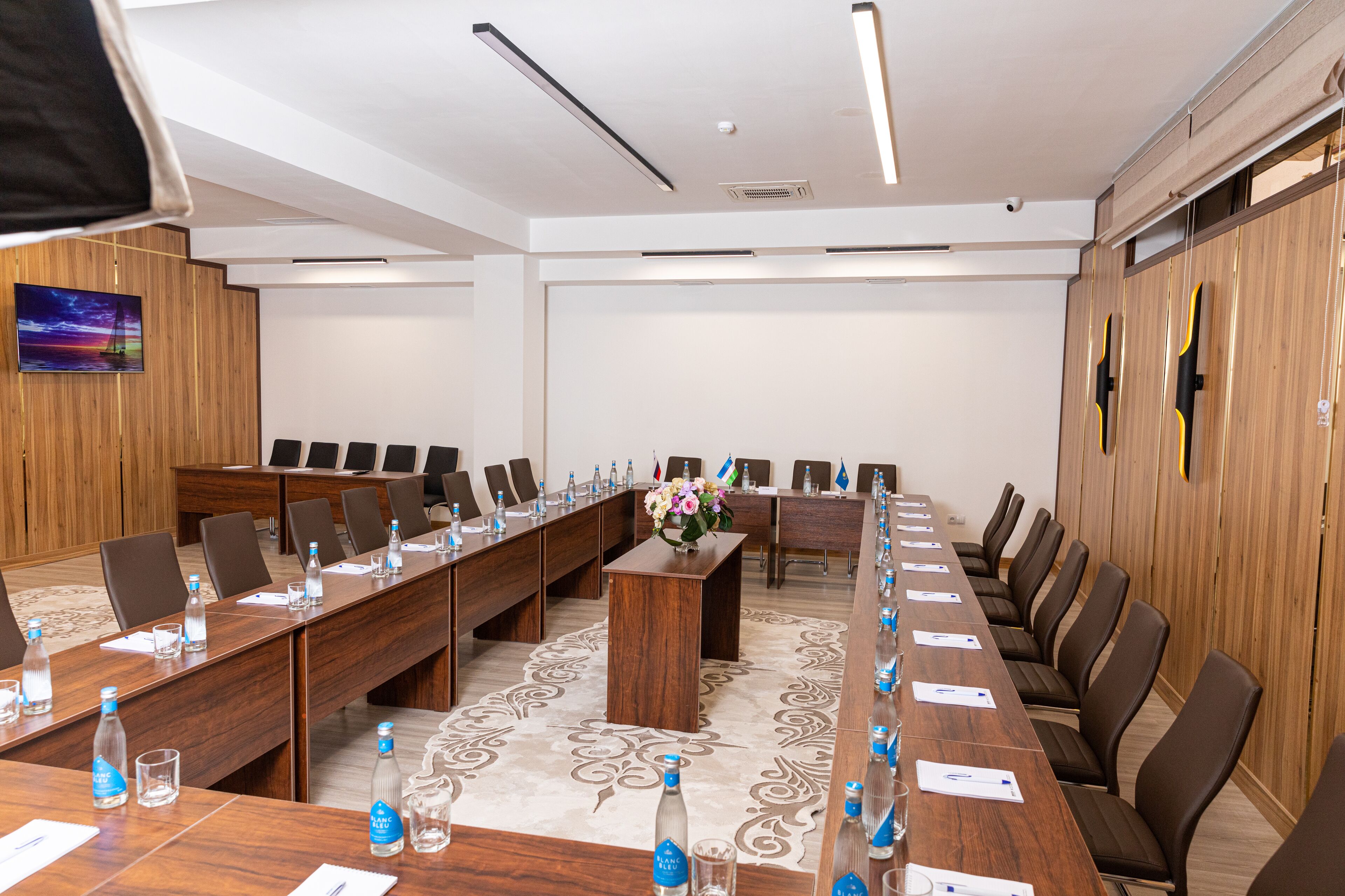 A conference room with a long table, chairs, and a wooden partition wall.