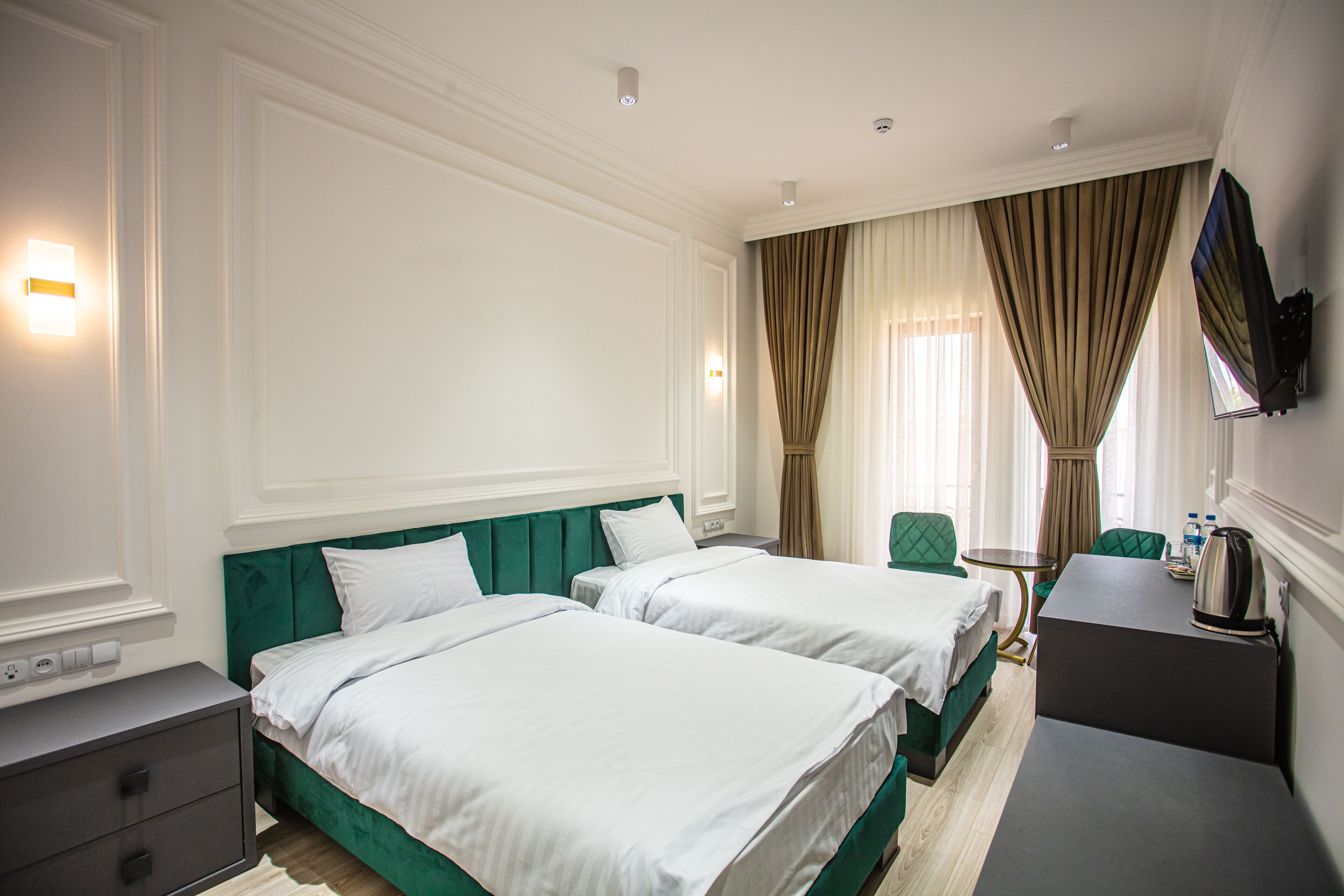 Une chambre d’hôtel avec deux lits, un bureau, une chaise et un téléviseur fixé au mur.