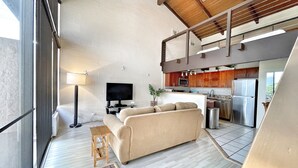 Un salón amplio con sofá, televisión y mesa de comedor.