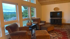 Una sala de estar con ventanas amplias, televisión y chimenea.