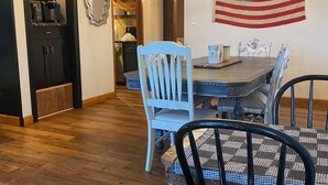 Un comedor con mesa de madera, sillas y una bandera estadounidense en la pared.