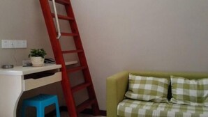 A room with a white desk, a red ladder, a blue stool, and a green sofa with checkered cushions. - Buding Inn (Yi County)