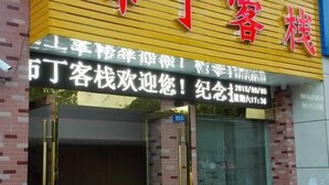 A hotel entrance with a sign in Chinese characters, a date and time on a digital display, and a number above the door. - Buding Inn (Yi County)