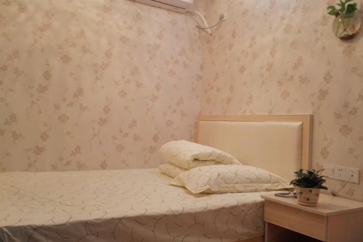 A bedroom with a bed, a nightstand, a wall-mounted plant, and floral wallpaper.