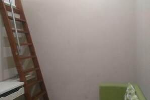 A room with a wooden ladder leaning against a wall, a green cushioned bench, and a white shelf unit. - Buding Inn (Yi County)