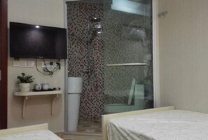 A hotel room with a bed, a TV mounted on the wall, a shower area with a glass door, and a small shelf with a plant and cups. - Buding Inn (Yi County)