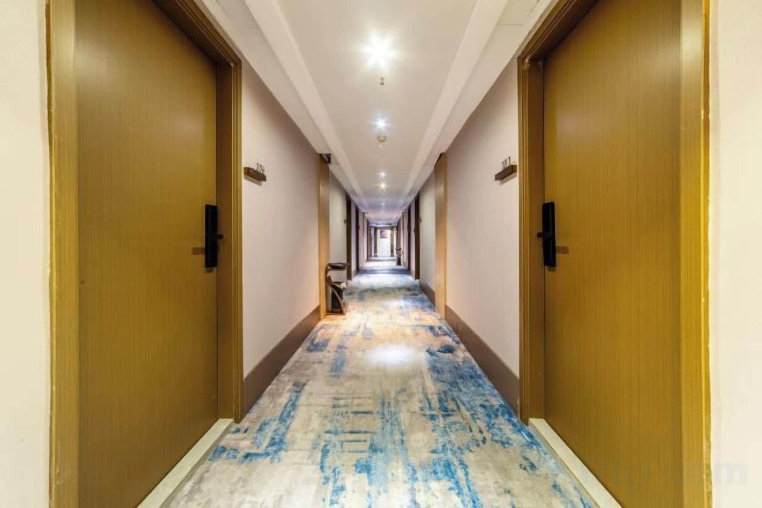 Ein Hotelgang mit Teppichböden, Holztüren und einer langen Strecke bis zum Ende.