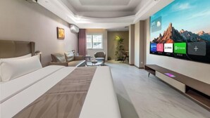 Ein Hotelzimmer mit Bett, Sofa, Wandfernseher und Fenster.