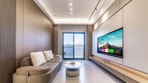 Ein modernes Wohnzimmer mit einer Couch, einem Couchtisch und einem großen Fernseher, der an der Wand befestigt ist.