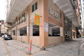 A building with multiple parking spaces and a sign indicating a business or service area. - Meiting Garden Apartment (Shantou)