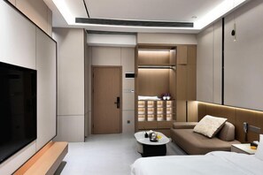 A modern hotel room with a large TV, a sofa, a bed, a small table, and a wardrobe. - Meiting Garden Apartment (Shantou)