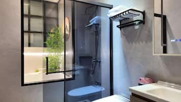 A modern bathroom with a glass-enclosed shower, a white sink, and a towel rack.