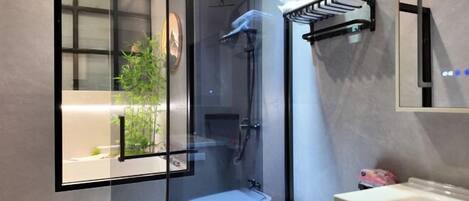 Ein modernes Badezimmer mit einer gläsernen Duschkabine, einem weißen Waschbecken und einem Handtuchhalter.