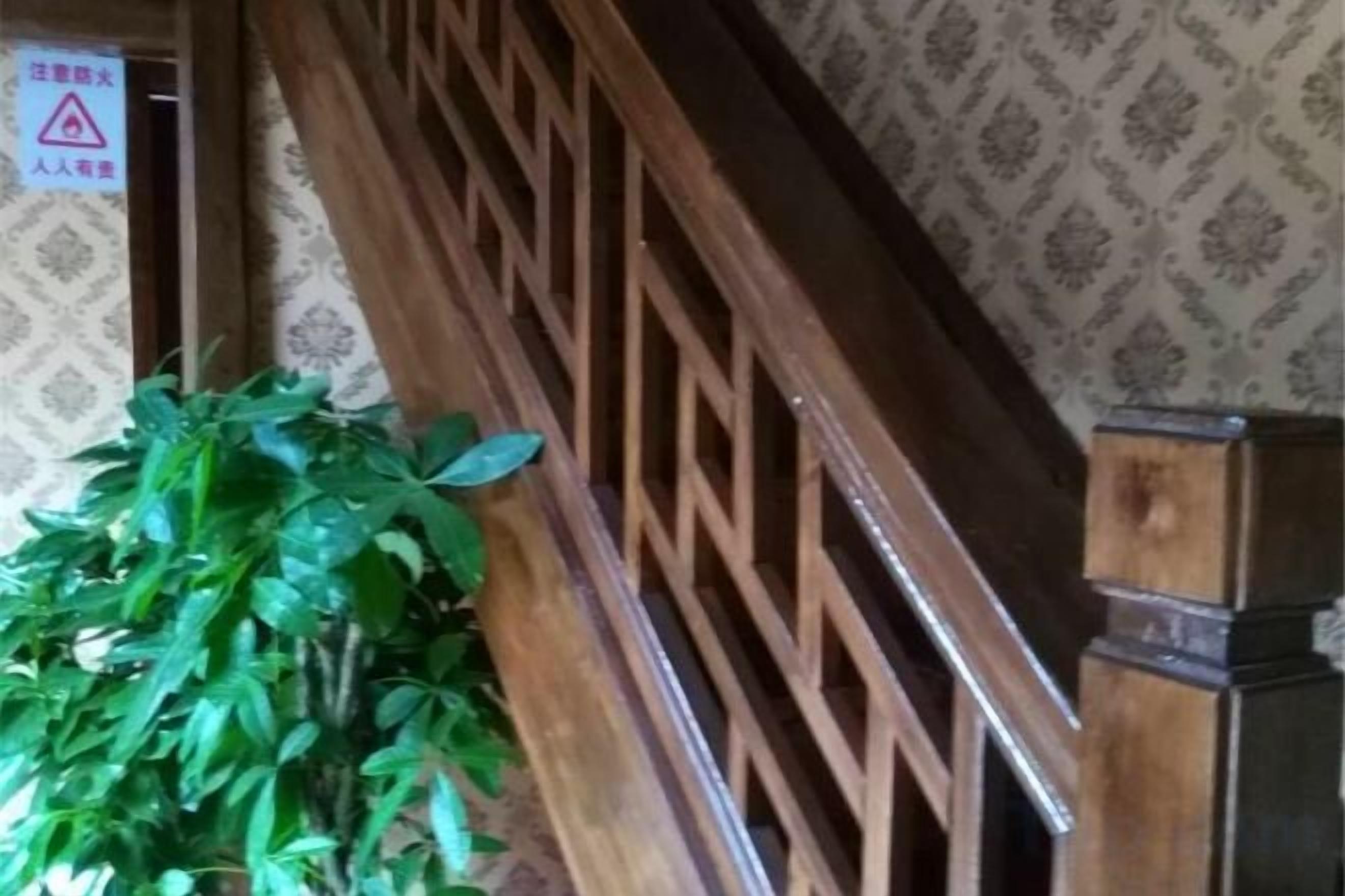 Una escalera de madera con un diseño geométrico, una planta en maceta y un papel tapiz estampado.