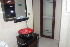 A kitchen with a black stove, a red frying pan, and a sink. - Xinyuan Mengya Inn (Langzhong)
