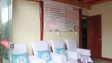 A waiting area with four chairs, a wooden ceiling, and a wall with a menu.