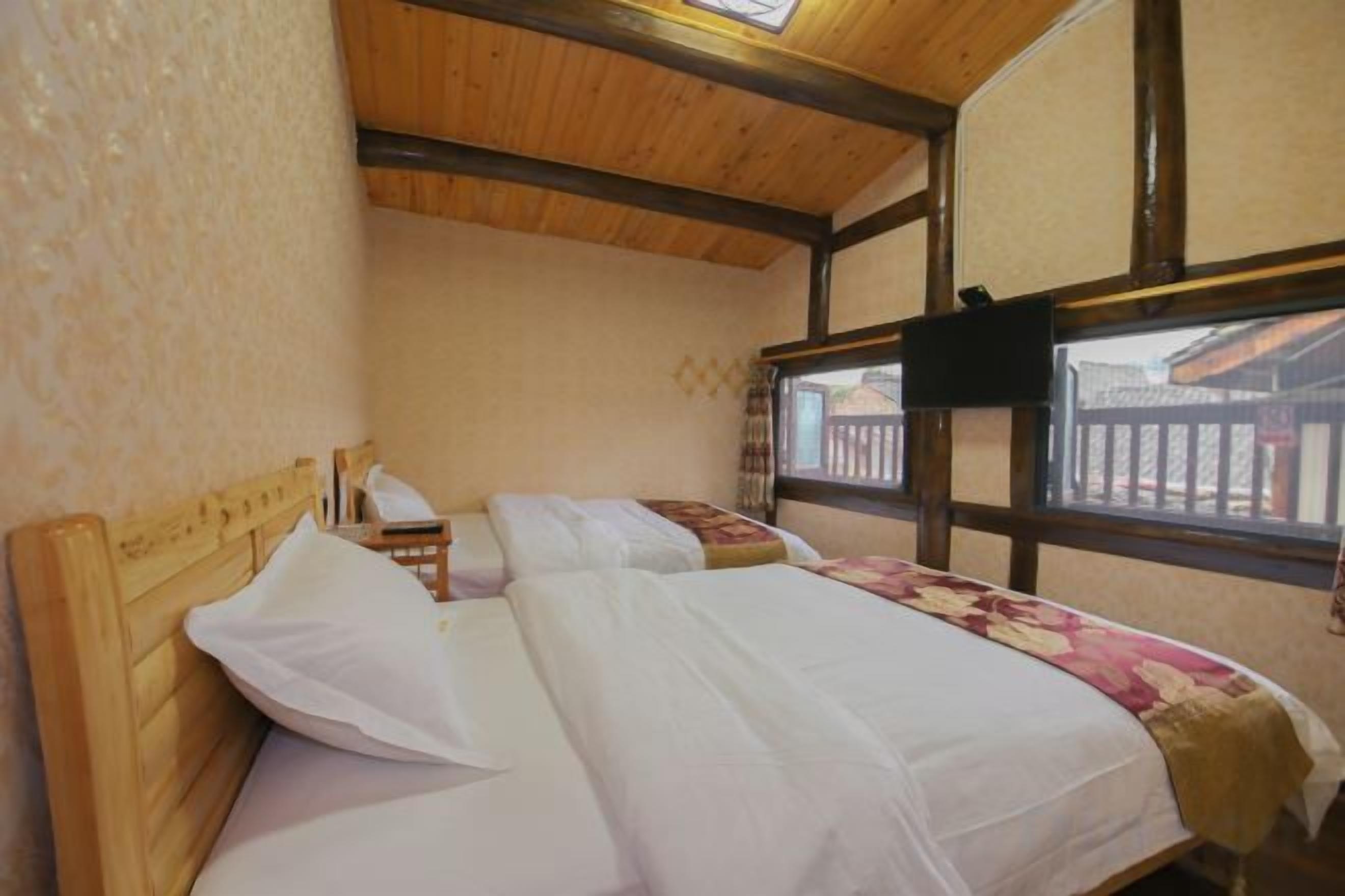 A room with two wooden beds, a window with a view, and a wooden ceiling.
