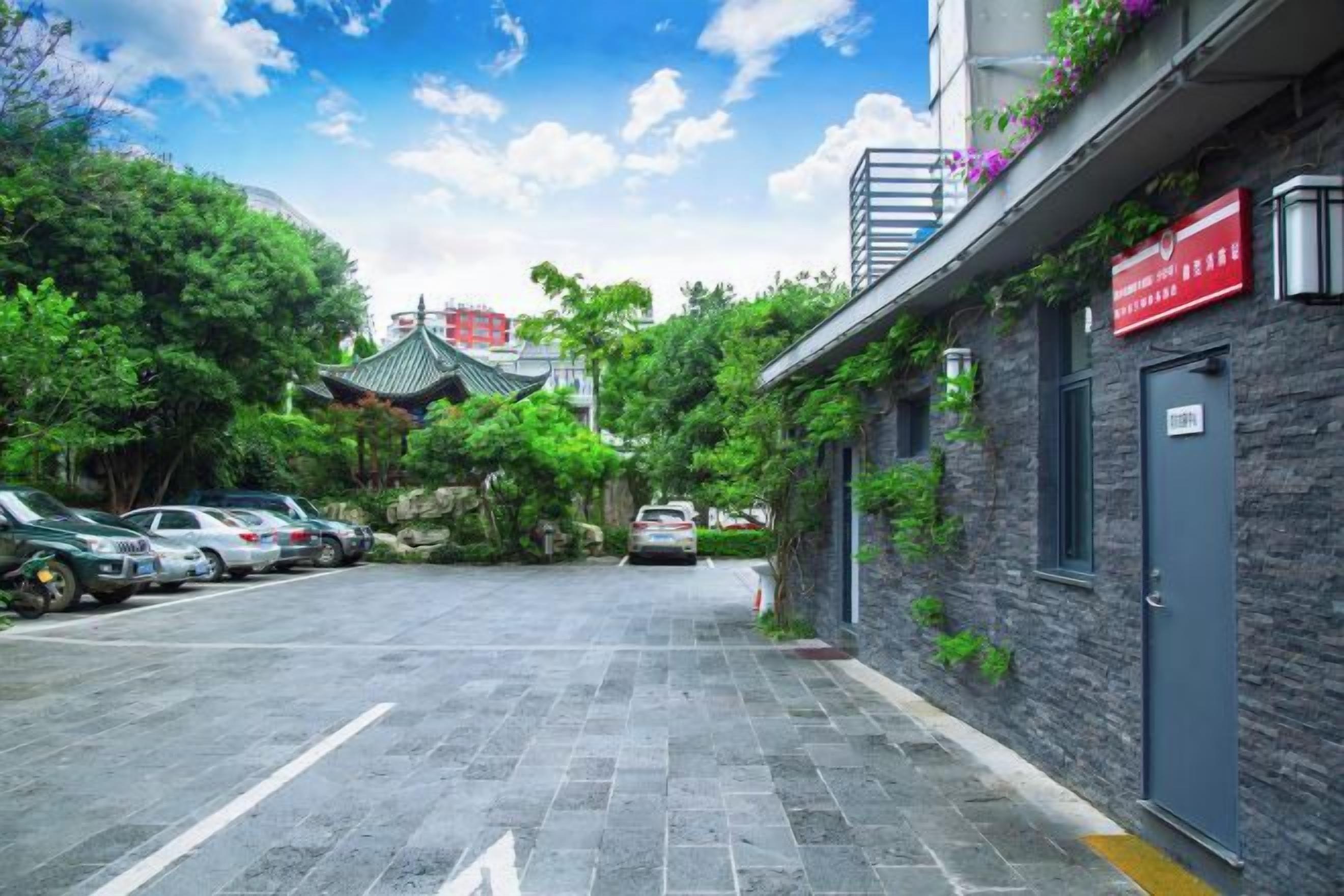 Un estacionamiento con coches, un edificio de fachada de piedra y un tejado de estilo coreano tradicional al fondo.