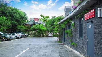 Un estacionamiento con coches, un edificio de fachada de piedra y un tejado de estilo coreano tradicional al fondo.