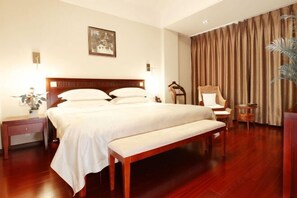 A hotel room with a large bed, bedside tables, a chair, a small table, and a curtain. - Landu Business Hotel (Tengchong)