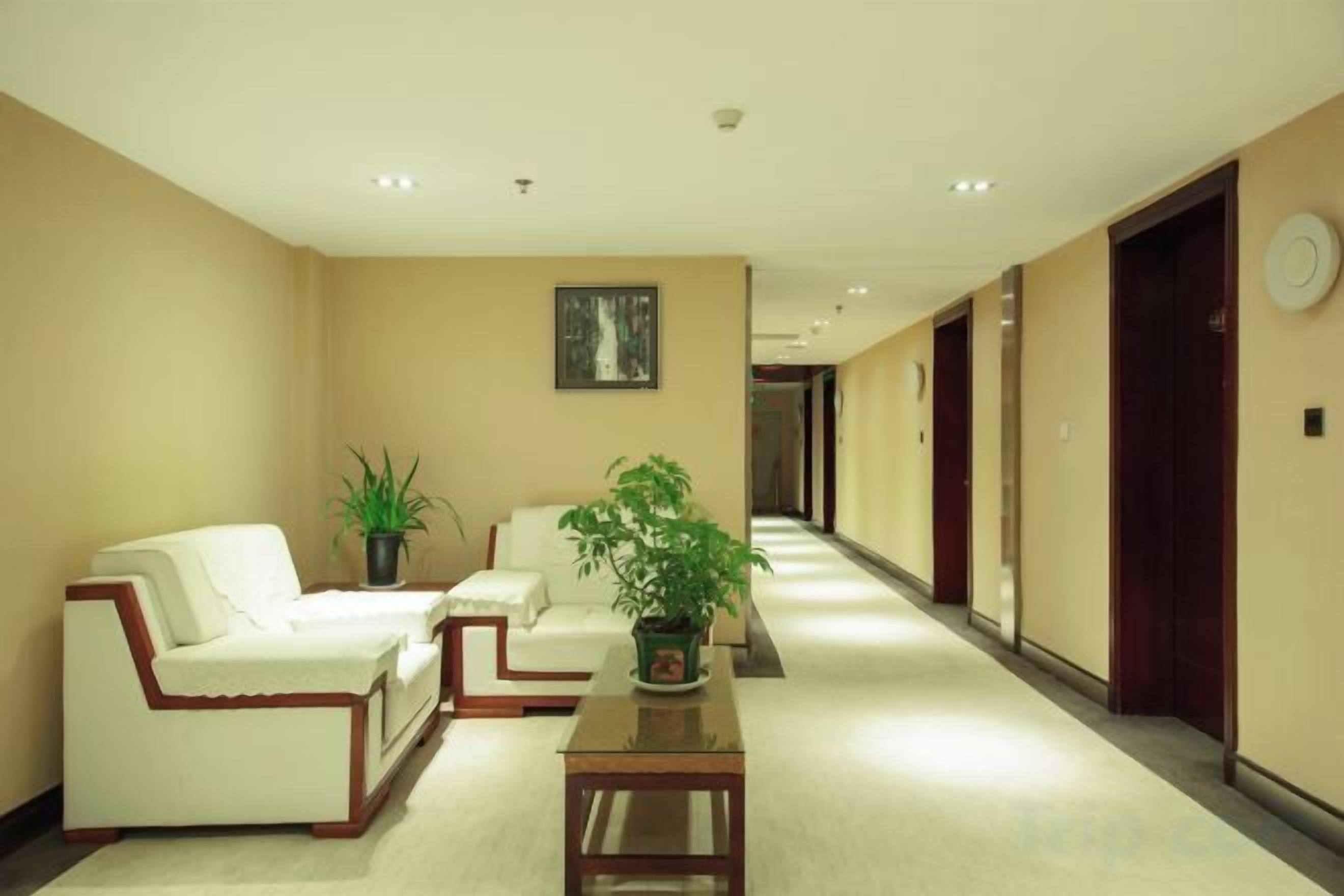 A hotel lobby with a reception desk, two sofas, a coffee table, and a potted plant.