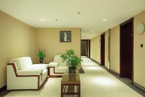 A hotel lobby with a reception desk, two sofas, a coffee table, and a potted plant. - Landu Business Hotel (Tengchong)